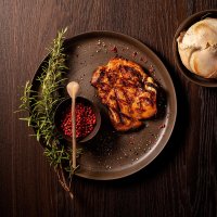 Grilled chicken leg with rosemary decoration, bowl with spices and wooden spoon