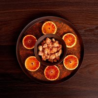 Citrus chicken breasts, flattened on bottom plate and flat plate with decorative orange slices
