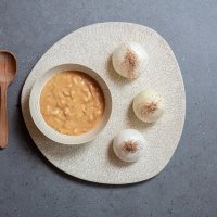 Onion soup with wooden spoon and three whole white onions